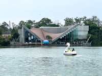 a white swan is floating in the water near a building